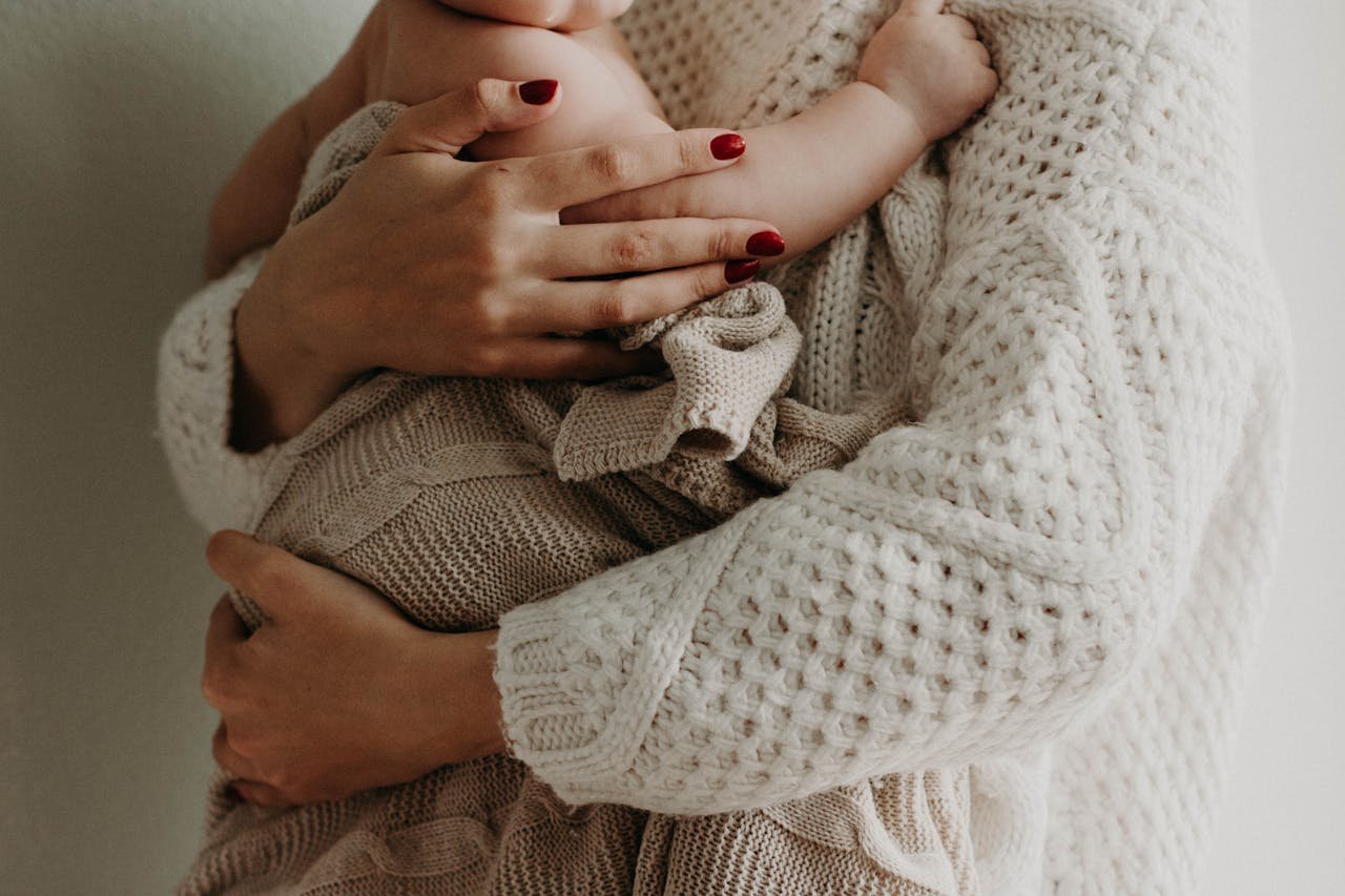creative-approach-img Close-up of a mother holding her baby in warm knitwear, conveying love and togetherness.