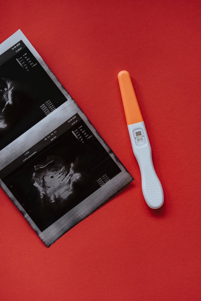 portfolio-05 Close-up of a positive pregnancy test with ultrasound scans on a vibrant red surface, symbolizing pregnancy confirmation.